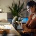Beauty business woman sending messages with mobile phone while working with computer in the office.