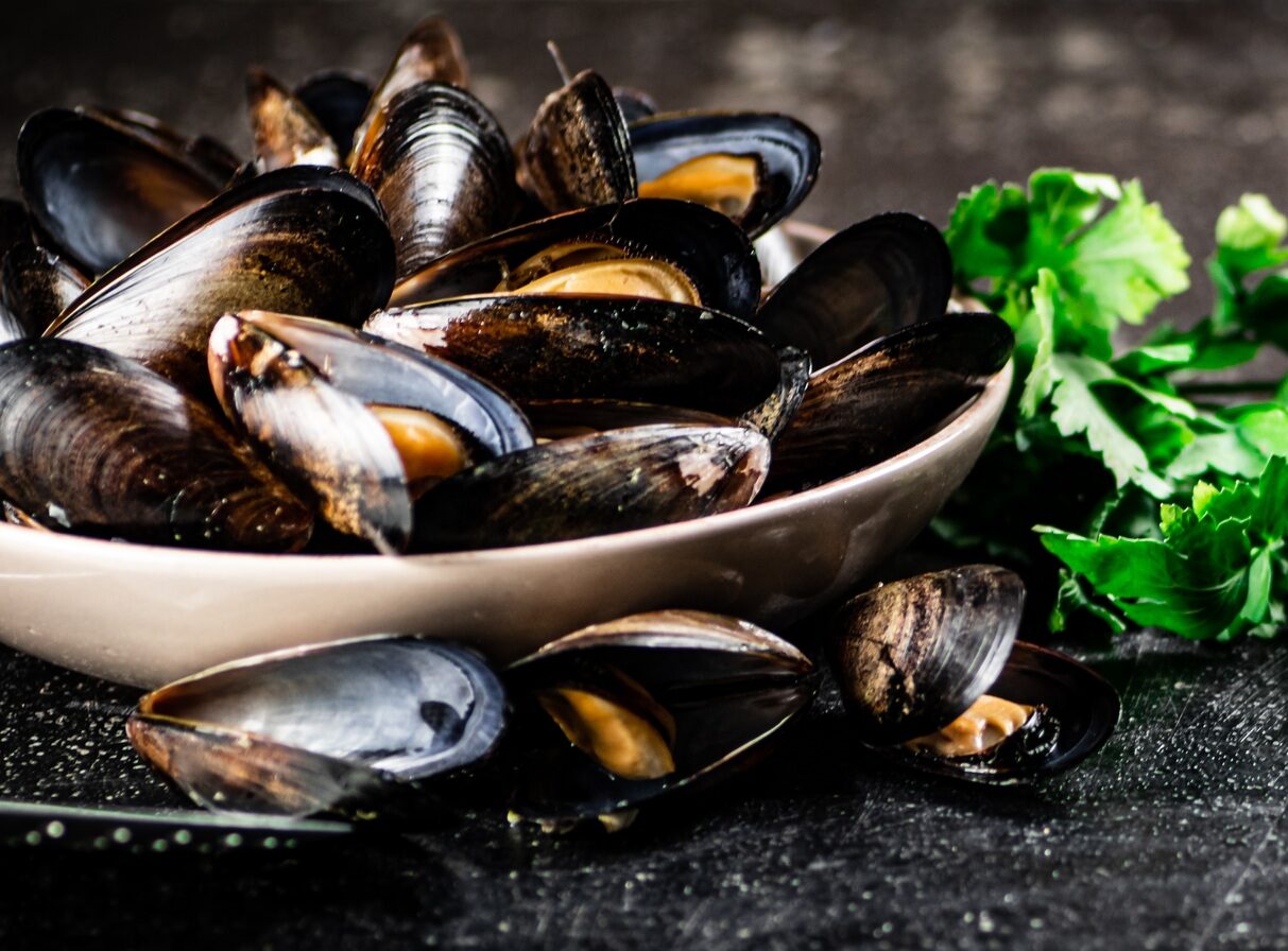 Boiled mussels in a bowl with parsley.