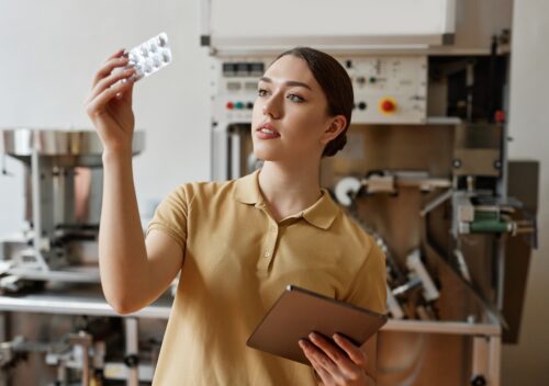 Young woman pills blister at pharmaceutical factory